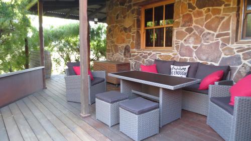 a patio with a table and chairs on a deck at Stone Creek Cottage in Barwite