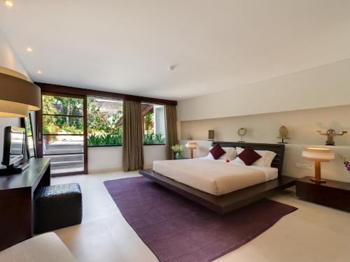a bedroom with a bed and a desk and a television at The Layar - Designer Villas and Spa, CHSE Certified in Seminyak