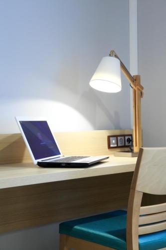 a laptop computer sitting on a desk with a lamp at The Originals City, L'Haut' Aile, Coquelles-Calais Tunnel s/Manche L'HAUTAILE in Coquelles