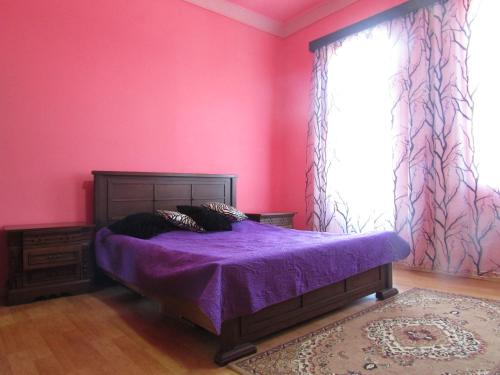 a bedroom with pink walls and a bed with purple sheets at Joni Guest House in Batumi