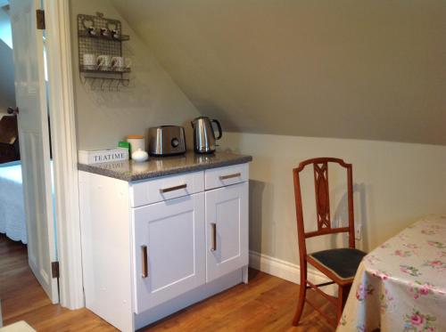 a kitchen with a counter and a table and a chair at Field Cottage B&B in Haywards Heath
