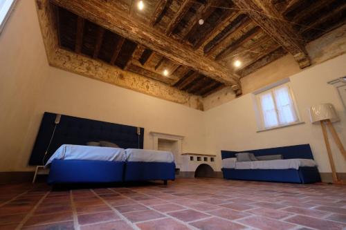 a large room with two beds and a ceiling with beams at Palazzo Sacco Hostello Fossano in Fossano