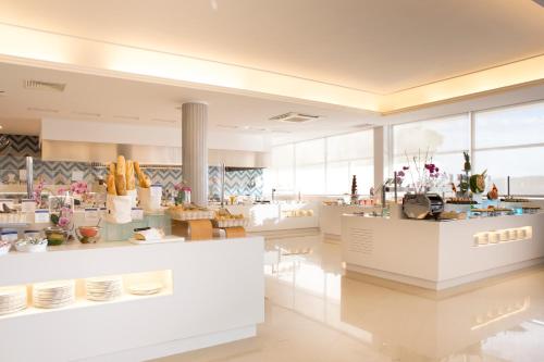 een restaurant met witte toonbanken, tafels en ramen bij Bahia Principe Sunlight Coral Playa - Adults Only in Magaluf