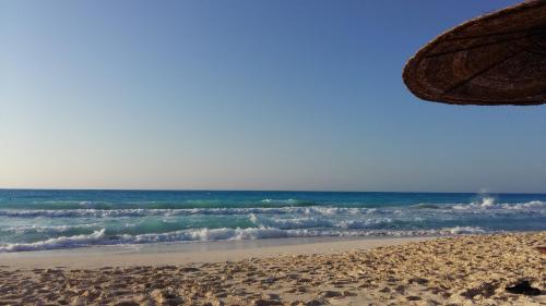 a beach with an umbrella and the ocean at El Zohour Chalet North Coast in El Alamein