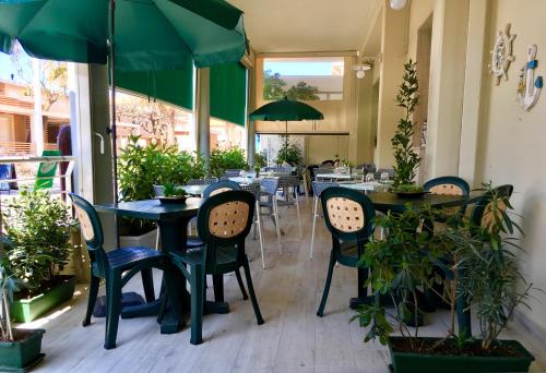 a restaurant with tables and chairs and green umbrellas at Lungomare Hotel in Marina di Cecina