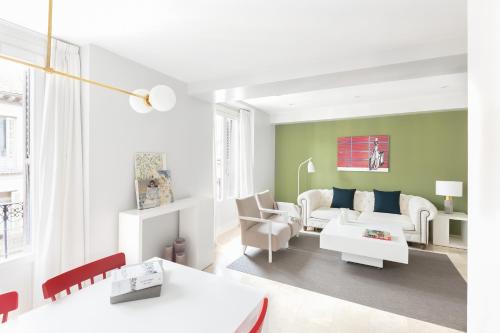 un salon avec des meubles blancs et des murs verts dans l'établissement Carretas Apartments, à Madrid