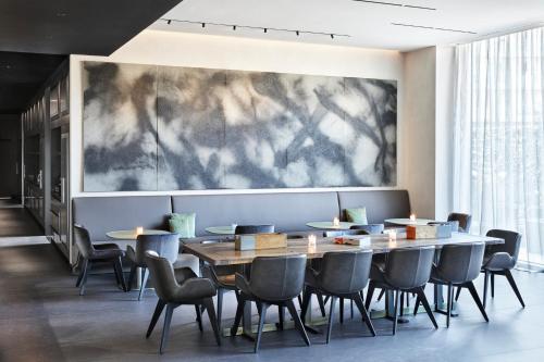 a dining room with tables and chairs and a large painting on the wall at Hotel VIU Milan, a Member of Design Hotels in Milan