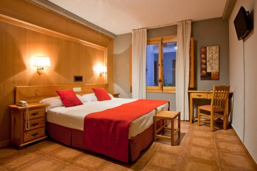 a bedroom with a large bed with a red blanket at Hotel Real De Toledo in Toledo