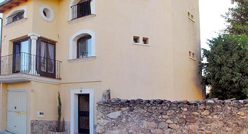 a large house with a stone wall in front of it at Casita Del Brezal in Rascafría