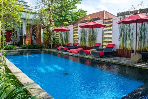 a swimming pool with chairs and umbrellas in a yard at Kamar Kamar Boutique Hotel in Seminyak
