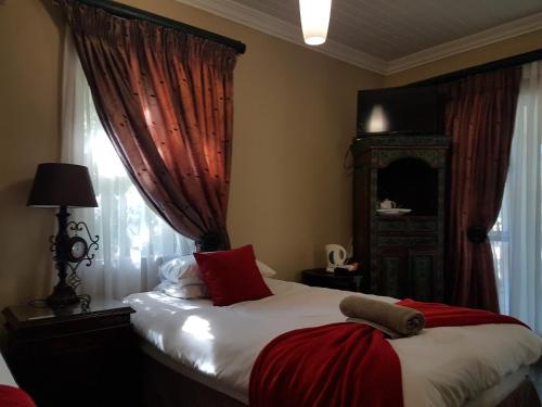 a bedroom with a bed with red and white sheets and a window at Santai guesthouse in Brits
