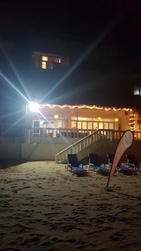 a beach with chairs and a surfboard in the sand at night at Coral Seas Beach Hikkaduwa in Hikkaduwa
