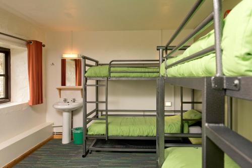 a room with three bunk beds and a sink at YHA Dartmoor in Postbridge