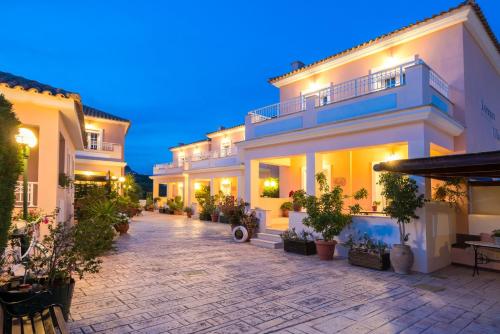 a large white building with potted plants in a courtyard at Lorenzo Villas with Private Pool, 200m from the beach, by ZanteWize in Lithakia
