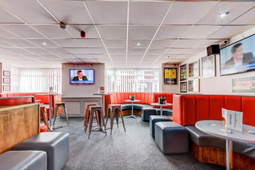 a restaurant with red booths and tables and a flat screen tv at The Sandringham Court Hotel & Apartment Welcoming Large and Small Groups for 16 years in Blackpool