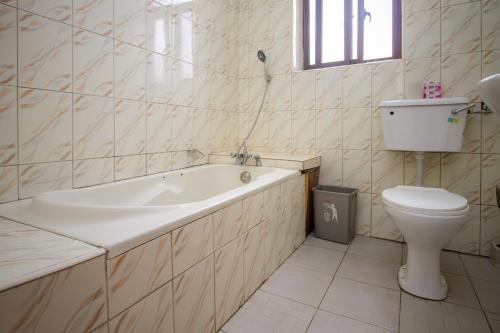 a bathroom with a tub and a toilet and a sink at Tiptone Hotel in Kampala
