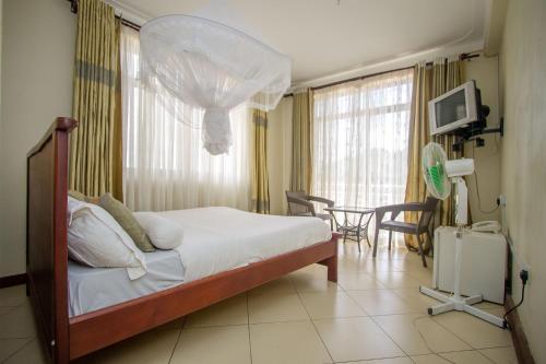a bedroom with a bed and a table and chairs at Tiptone Hotel in Kampala