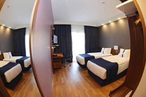 マニサにあるHoliday Inn Express Manisa-West, an IHG Hotelのベッド3台と鏡が備わるホテルルーム