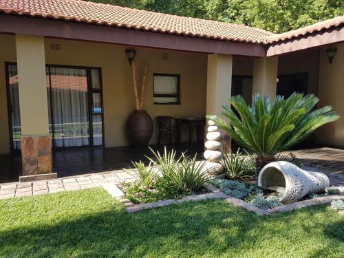a house with a patio and a yard with plants at Santai guesthouse in Brits