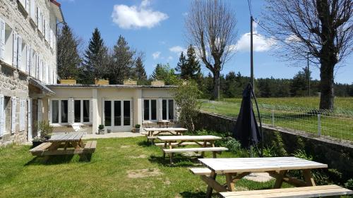 a group of picnic tables in front of a building at Maison La Vigne - Gîtes et Chambres d'hôtes in Le Chambon-sur-Lignon