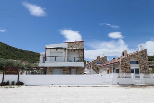 a white fence in front of a house at Petritis Villas in Iraklitsa