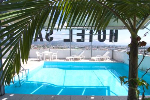 a pool on the roof of a building with a palm tree at Hotel San Silvestre in Tubarão