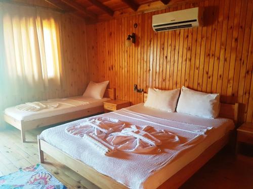 a bedroom with two beds in a room with wooden walls at Ada Adrasan Hotel in Adrasan