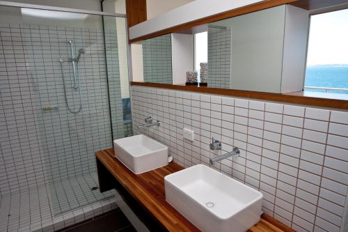 a bathroom with two white sinks and a shower at Penthouse on Bright Point in Nelly Bay