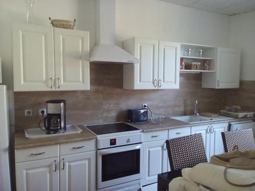 une cuisine avec des armoires blanches et un four à plaques de cuisson dans l'établissement La Vadrouille, à Sigean