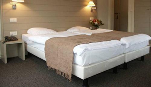 a bedroom with a large bed with white sheets and pillows at Hotel Atlas in Zeebrugge