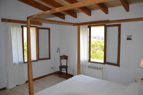 1 Schlafzimmer mit einem Bett, 2 Fenstern und einem Stuhl in der Unterkunft Es Campet in Sóller