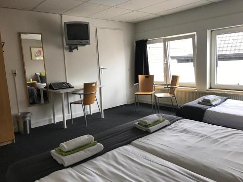 Cette chambre d'hôtel comprend deux lits, une table et des chaises. dans l'établissement Stadshotel Ter Stege, à Oldenzaal