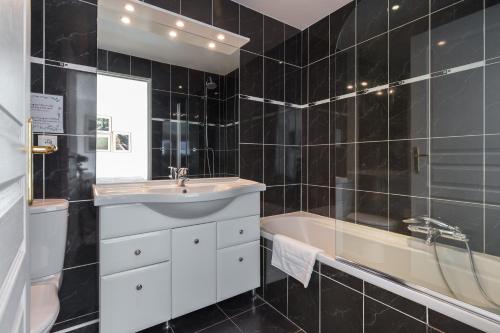 La salle de bains est pourvue de carrelage noir, d'un lavabo et d'une baignoire. dans l'établissement Superb penthouse in centre of Cannes Stunning views air-conditioning internet Near the Palais 532, à Cannes
