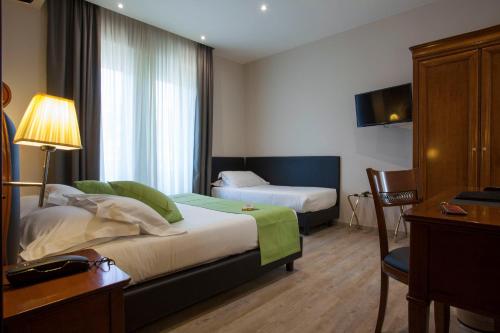 Habitación de hotel con 2 camas, escritorio y TV. en Hotel Astoria en Rapallo