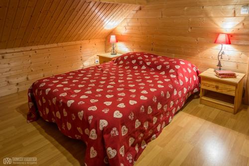 een slaapkamer met een rood bed in een houten kamer bij LE QUARTZ DES HAUTES-VOSGES in Xonrupt-Longemer