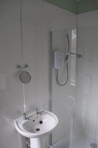 a white bathroom with a sink and a shower at Cumberland Inn in Alston