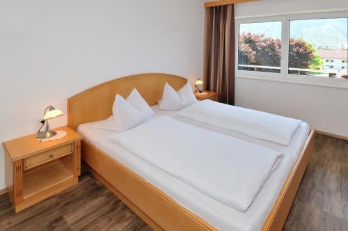 a bedroom with a large white bed with a window at Pension Apartment Hödner in Ebbs