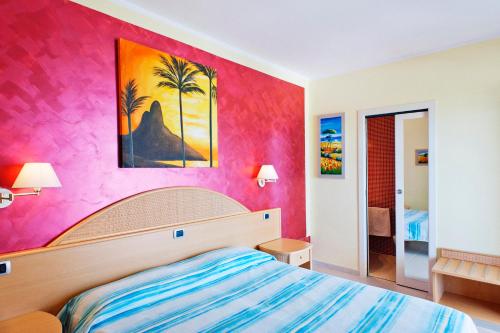 a bedroom with a bed and a pink wall at Hotel La Tramontana in San Domino