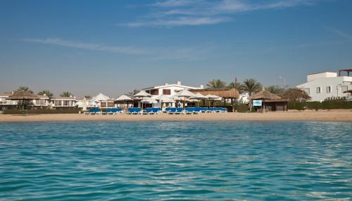 a beach with houses and chairs and the water at Jaz Little Venice Golf Resort in Ain Sokhna