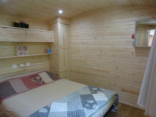 a bedroom with a bed in a wooden room at La Roulotte in Châtillon-en-Diois