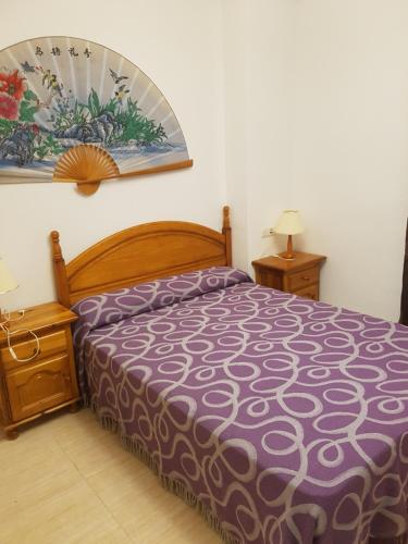 a bedroom with a bed with a purple bedspread at Apartamento Costa Marina III Magic World in Oropesa del Mar