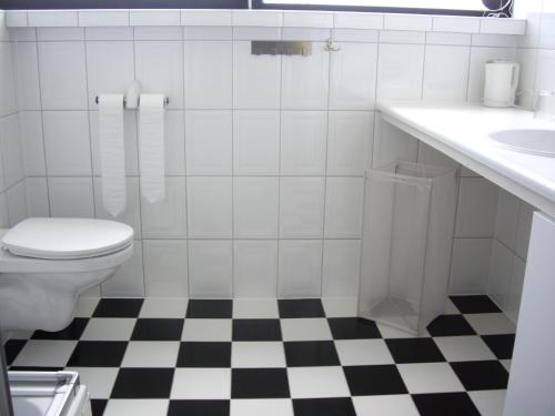 ein weißes Bad mit schwarz-weißem, kariertem Boden in der Unterkunft Bed & Breakfast aan Zee in Callantsoog