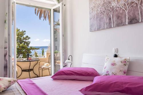a bedroom with purple pillows and a view of a balcony at Apartment Dujić with hot tub in Kaštela