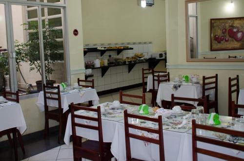 a dining room with white tables and chairs at Hotel Majú in Rio Branco