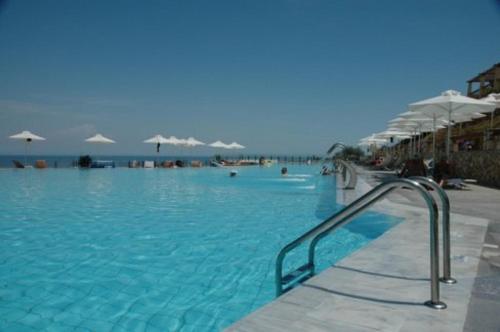a swimming pool with blue water and white umbrellas at Villa Apostolata in Skala Kefalonias