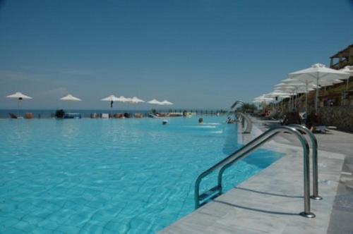 a swimming pool with blue water and white umbrellas at Villa Apostolata in Skala