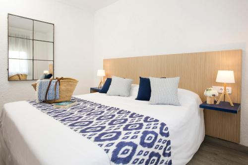 a bedroom with a large white bed with blue pillows at Pierre & Vacances Blanes Playa in Blanes