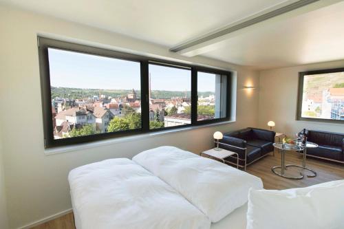 1 dormitorio con cama blanca y ventanas grandes en MAVO Hospitality by Büroma Apart Apartmentvermietung GmbH Esslingen en Esslingen