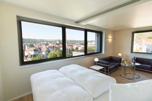 a bedroom with a white bed and large windows at MAVO Hospitality Esslingen Berliner Straße in Esslingen