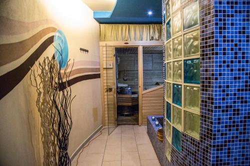 a bathroom with blue tiles on the walls and a tub at Hotel Centrum Harrachov in Harrachov